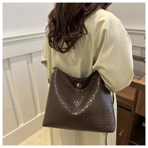 Detailed view of dark brown woven leather tote with gold chain and circular swivel clasp