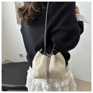 Detail of cream plush bucket bag with chain strap and pearl drawstring charms