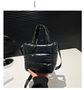 Detailed view of black quilted puffer handbag with glossy finish and adjustable strap