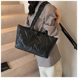 Detail of black quilted puffer tote bag with ruffled straps and V-shaped stitching
