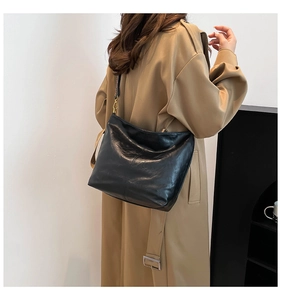 Detail of vintage black bucket bag with a patterned wide woven strap on a female model