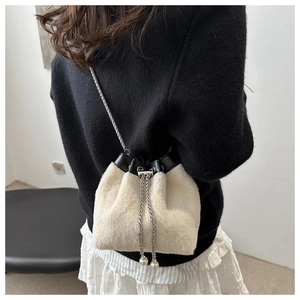 Detail of plush bucket bag with faux fur texture, silver chain and pearl drawstring charms