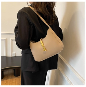 Close-up of beige shoulder bag with a sleek gold rectangular twist lock mechanism