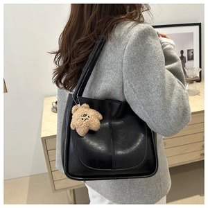 Gros plan d'un sac cabas en cuir noir avec breloque en peluche pour le style quotidien