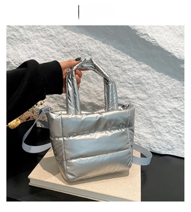 Close-up of metallic silver quilted tote bag with detachable strap and puffer texture