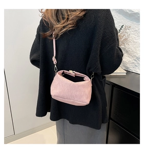 Detail of pink half-moon crossbody bag with adjustable strap worn on dark outfit