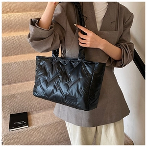 Detail view of black quilted puffer tote bag with V-shaped stitching and puffy texture