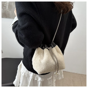 Detail of white plush bucket bag with silver chain strap and pearl drawstring tassels