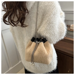 Detail of beige faux fur bucket bag featuring pearl charms and silver chain strap