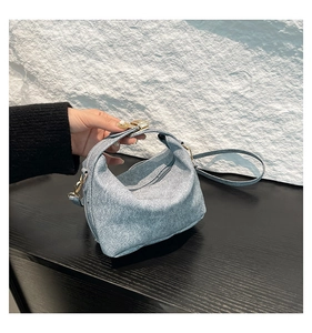 Close-up of light blue denim-textured handbag with silver shimmer and gold hardware