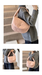Close-up of a light pink quilted puffer tote bag with a wide strap on a gray sweater