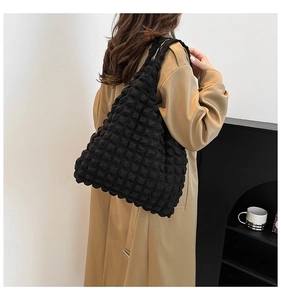 Close-up of black bubble textured tote bag shoulder strap and fabric on a model