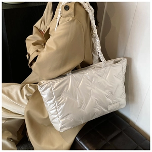 Detail of glossy quilted white tote bag featuring unique ruffled shoulder strap design