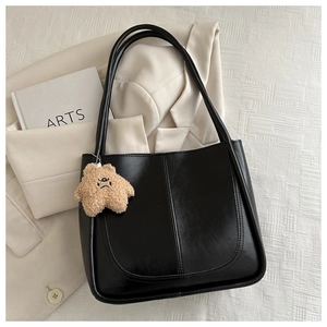 Détail du sac cabas noir en similicuir avec un charm étoile sur un fond minimaliste