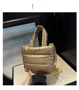 Detail of a quilted gold puffer bag with plush texture and detachable shoulder strap