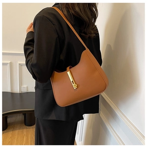 Detail of caramel leather shoulder bag featuring a sleek vertical gold metal lock buckle