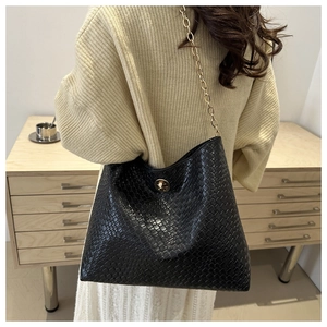 Close-up of black woven leather texture and gold chain strap on shoulder bag