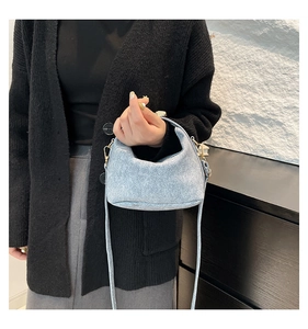 Close-up of light blue denim texture bag with gold hardware and stylish saddle shape