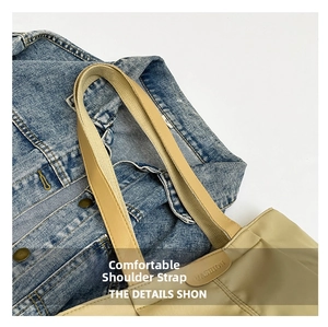 Detail of reinforced khaki canvas tote bag strap with FASHION leather patch on denim