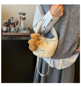 Detail of white plush bucket bag featuring a brown teddy bear charm and logo tag
