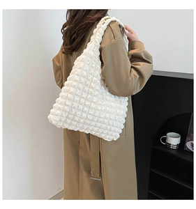 Minimalist white bubble textured tote bag shown on model with pleated fabric detail