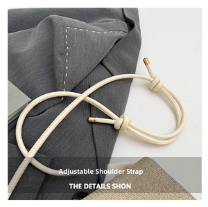 Detail of adjustable off-white leather strap with knotted design and gold metal tips