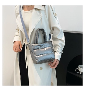 Detail of silver quilted puffer bucket bag with metallic finish and fabric shoulder strap