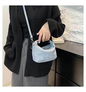Close-up of a light blue textured mini crossbody bag with top handle and strap details
