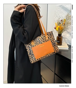 Detail of leopard print tote bag with orange leather pocket and fashion branding