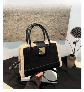 Details der schwarzen Handtasche aus Mattleder mit cremefarbenem Kunstfellbesatz und Schnalle