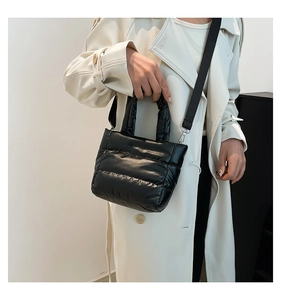 Close-up of black quilted puffer shoulder bag with glossy nylon finish and metal hooks
