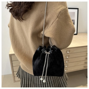 Black faux fur bucket bag with silver chain strap and pearl drawstring on a model