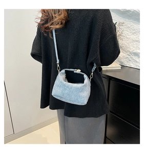 Close-up of a light blue textured crossbody bag styled with a black knit outfit