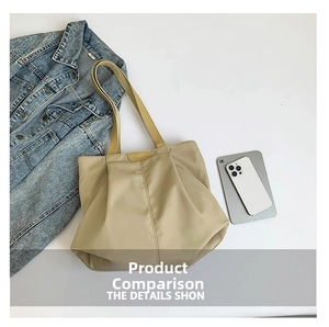 Detailed view of khaki pleated tote bag with FASHION patch on casual denim backdrop