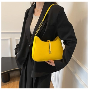 Close-up of vibrant yellow underarm bag with gold chain and metal buckle on a model