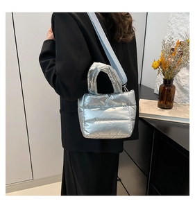 Detail of silver quilted bucket bag featuring a wide blue strap and metallic finish