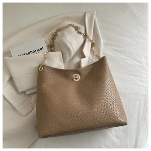 Detail of woven brown leather texture and golden chain strap on a stylish shoulder bag