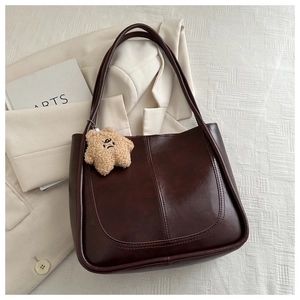 Detail of vintage brown leather bucket tote bag with star plush charm on a white fabric