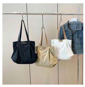 Three minimalist tote bags in black, beige and white colors shown in a hanging display
