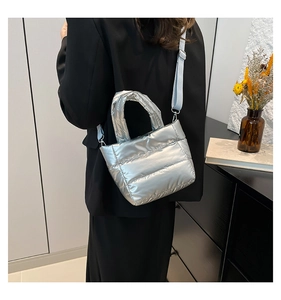 Modern metallic silver quilted puffer bag shown on model with light blue strap