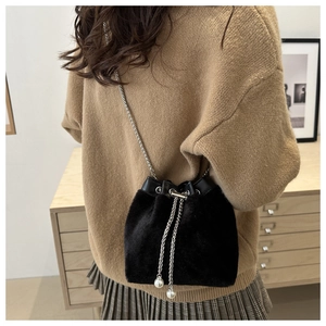 Détail d'un sac seau en peluche noire avec chaîne argentée et perles blanches décoratives