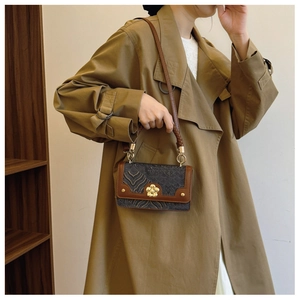 Détail du sac bandoulière bleu marine embossé avec bordure marron et fermoir fleur dorée