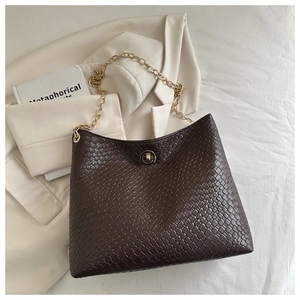 Detail of dark brown woven shoulder bag with gold chain and circular metal lock