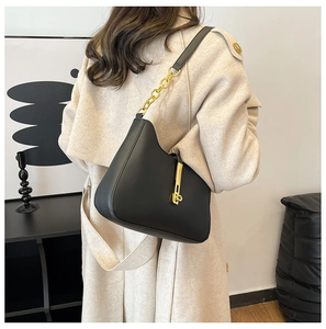 Close-up of black leather underarm bag with gold chain strap and metallic buckle