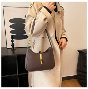 Detail of dark brown leather hobo bag featuring vintage gold piston lock and chain strap