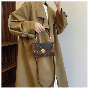 Détail du sac à main rétro avec fermoir floral doré et poignée tressée sur un modèle