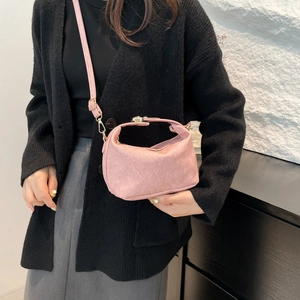 Pink crescent shoulder bag with metallic clasp and adjustable strap worn by model