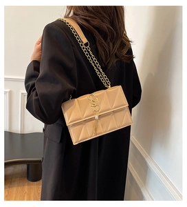 Detail of beige quilted shoulder bag with gold chain strap and stylish tassel pendant
