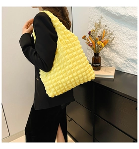 Detail of yellow popcorn fabric tote bag with textured ruffles on woman's shoulder