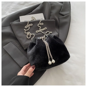 Detail of black faux fur bucket bag with metal chain strap and pearl drawstring charms